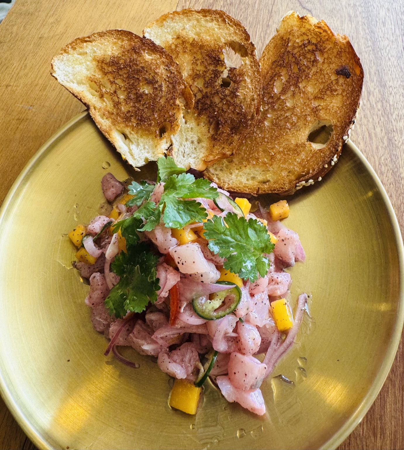 A colourful dish topped with fresh herbs and served with golden toast on a yellow plate
